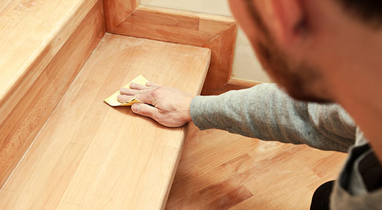 Man sanding wooden staircase